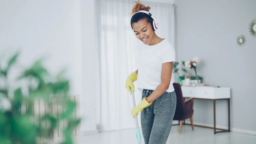 A woman carefully covers a sofa with protective wrap while packing boxes in a bright room.